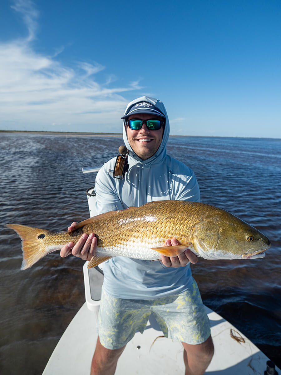 Angler holding a beautiful redfish caught fly fishing in Texas